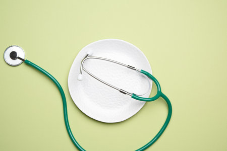 round white ceramic plate and medical stethoscope on green background, healthy food conceptの写真素材