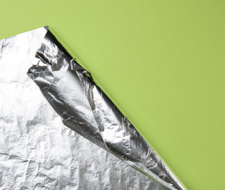 rolled sheet of foil on a green background, the corner is folded, copy spaceの写真素材