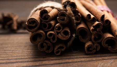 tied bunch of brown cinnamon sticks on a wooden background, close up