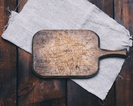 old brown rectangular wooden kitchen cutting board and gray linen napkin on the table, top viewの写真素材