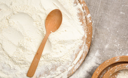 white wheat flour in a wooden spoon, top view, close upの写真素材