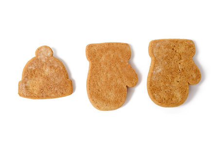baked christmas gingerbread cookies in the form of mittens and hats isolated on white background, blank for paintingの写真素材
