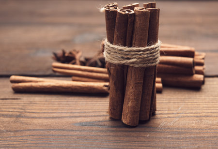 tied bunch of brown cinnamon sticks on a wooden background, close up