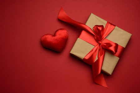 square box with red silk bow and textile heart on red background, top view, valentine's dayの写真素材