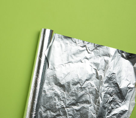 rolled sheet of foil on a green background, the corner is folded, flat layの写真素材