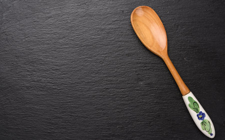 empty vintage wooden spoon with ceramic handle on black background, top viewの写真素材