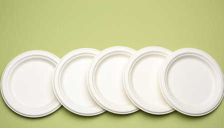 empty white paper disposable plates on a green background, top view. The concept of rejection of plastic, environmental conservationの写真素材