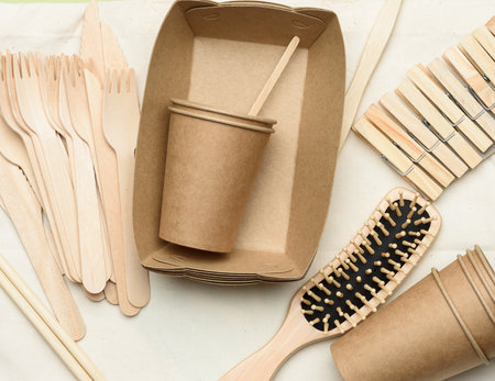 white textile bag and disposable tableware from brown craft paper on a green background. View from above, plastic rejection concept, zero wasteの写真素材