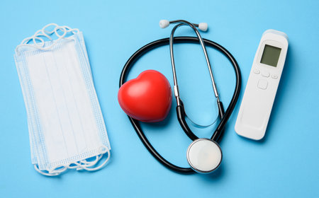 non-contact thermometer, stethoscope and a stack of masks on a blue background, top viewの写真素材