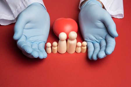 family of wooden figures and two hands in blue latex gloves, protection and patronage, insuranceの写真素材