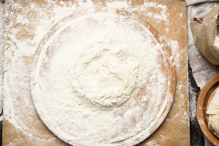 white wheat flour heaped on a round wooden board, top view