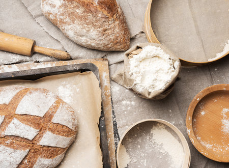 bread and white wheat flour in a bag, wooden rock and plate, top view