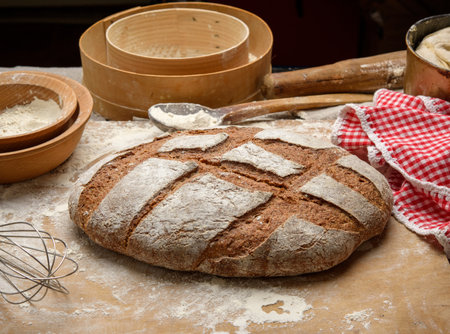 baked loaf of bread on the table and ingredients, kitchen utensils lie nearby, top view