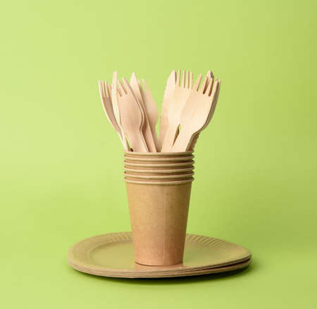 brown paper cup, plates on a green background. Plastic rejection concept, zero waste, close up