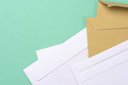 blank white paper brown and white envelopes on a green background, copy space