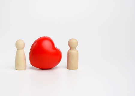 pair of wooden men of the bride and groom, between them a red heart, white background, the concept...
