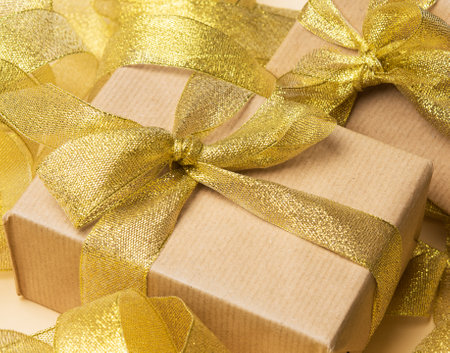 gift wrapped in brown paper on a twisted golden ribbon background, festive background, top viewの写真素材