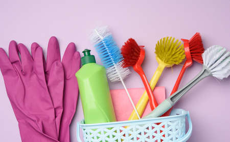 green plastic bottle and rubber gloves for cleaning, brushes on a purple background, flat lay,...