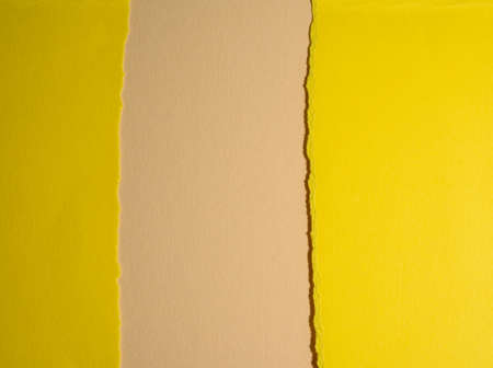 torn edges of yellow cardboard on a beige background, abstract background with shadows, copy space
