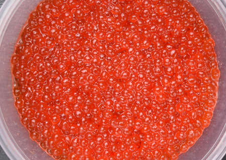 fresh red chum salmon caviar in a plastic plate on a black background, top viewの写真素材