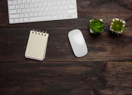 white wireless keyboard and mouse on a wooden brown table, top view, copy spaceの写真素材