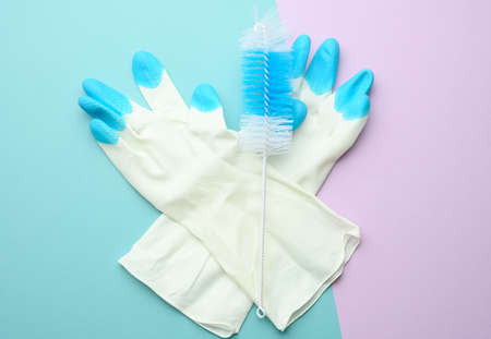 white rubber gloves for cleaning, brushes on a green background, flat lay