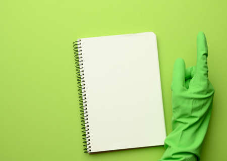 open paper notebook with blank white sheets, green background, copy space
