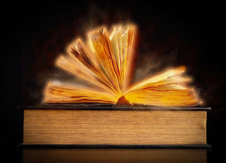 open old vintage book on black background, golden haze around