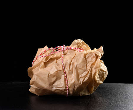 wrapped in brown kraft paper object and tied with rope, packaging on a black background, close upの写真素材