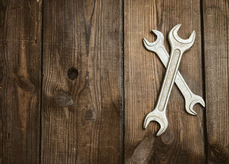 two metal adjustable wrenches on a brown wooden background, top viewの写真素材