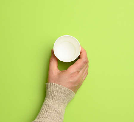 female hand holding empty paper disposable cup on green background, concept eco-friendly, zero waste, top viewの写真素材