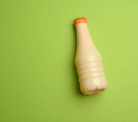 beige plastic bottle for milk on a blue background, container for liquid products, flat layの写真素材