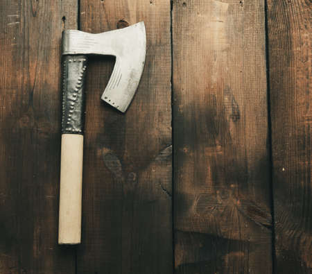 metal vintage ax with wooden handle on brown wooden background, top view, copy spaceの写真素材
