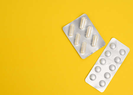 round pills in blister packs on a yellow background, top view