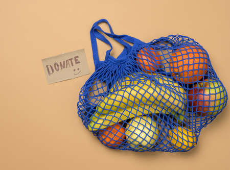 ripe fresh fruits in a textile string bag on a brown background, donating