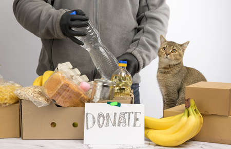 man collects food, fruits and things in a cardboard box to help the needy and the poor, help and...