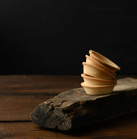 stack of baked round blank tartlets on wooden board, black background, copy spaceの写真素材