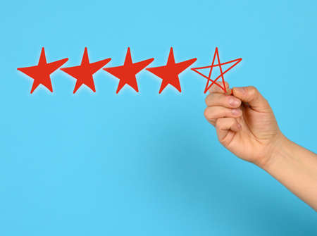 score five red stars and a female hand draws on a blue background, high rating, close up