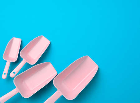 set of pink plastic kitchen scoops for bulk products on a blue background, flat layの写真素材