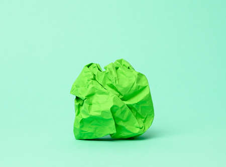 crumpled ball of green paper on a green background, close upの写真素材