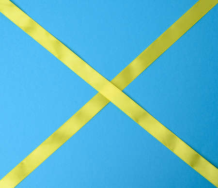 yellow silk ribbon on a blue background, top viewの写真素材