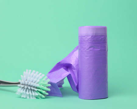 plastic brush and skein of purple plastic trash bags with strings on a green background, close upの写真素材