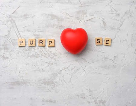 red heart and inscription purpose from wooden blocks on white cement backgroundの写真素材