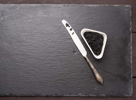 black grainy caviar of paddlefish fish in a white ceramic bowl, black background, top view, copy spaceの写真素材
