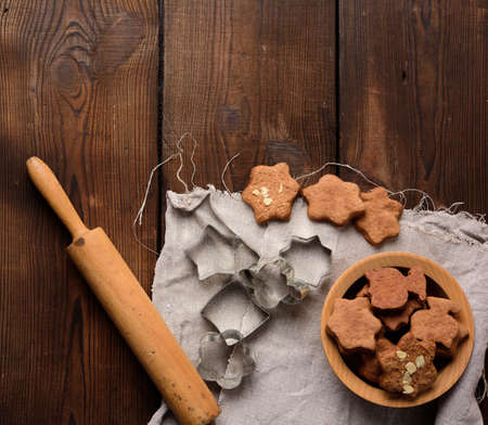 baked star shaped gingerbread cookies, wooden rolling pin and metal cutters on a black table, top viewの写真素材