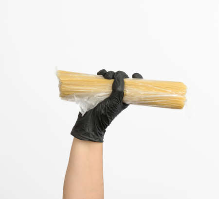 female hand in a black glove holds a transparent bag with spaghetti on a white backgroundの写真素材