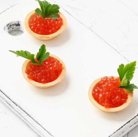 red caviar in a round tartlets on a white table, close upの写真素材