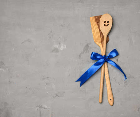 spoon and spatula tied with blue ribbon on gray background, top viewの写真素材