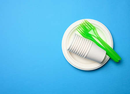 green plastic forks and empty white paper disposable plates on a blue background, top view, setの写真素材