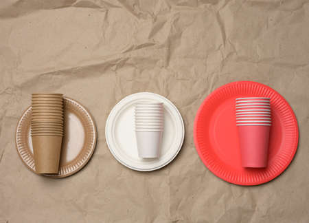 stack of paper cups and round plates on a brown paper background. Plastic rejection concept, zero wasteの写真素材